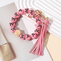 Détail du bracelet porte-clés en perles de bois rose avec pompon en cuir et fermoir doré - Rose