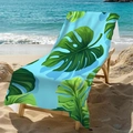 Green monstera leaf microfiber beach towel displayed on a beach lounge chair by the sea - Standard Size / Green Hawaii Leaves