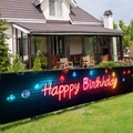 Outdoor banner for birthday parties featuring neon art text on a brick wall background - 200x40cm / Neon Happy Birthday