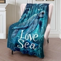 Manta de franela con estampado de tortuga marina azul sobre un sillón rosa en una sala acogedora - 100x150cm