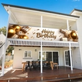 Golden balloon birthday banner hanging on a white terrace balcony against blue sky - 200x40cm / Golden Balloon