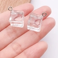 Detailopname van hars ijsblokjes hangers met metalen ringen vastgehouden in de hand - Klein Ijsblokje (24110) / 1 Stuk (14x12x12mm) / Helder Wit