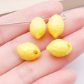 Dettaglio di una mini perla di limone in acrilico per gioielli fai-da-te nella mano - Limone in Acrilico Giallo Solido
