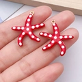 Detailed macro view of red enamel starfish charms with white dots and gold metal loops - Red Polka Dot Style / Large