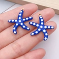 Detailed close-up of two blue starfish charms with white dots and gold metal edges - Royal Blue Polka Dot / Large