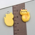 Close-up of yellow resin cat charms with metal loops shown against a metric ruler for size - 22x15x7mm / Yellow Resin Cat
