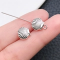 Zilveren schelpvormige bedel voor doe-het-zelf sieraden en oorbellen op vinger - Schelp Tussenkraal Stijl (15976) / Antiek Zilver