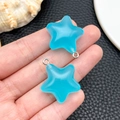 Detail of semi-transparent blue resin star pendants with silver metal loops held in hand - Blue Luminous Star (24065)