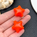 Detail of 3D orange resin star charms with silver rings held in hand for size - Orange Luminous Star (24063)