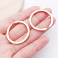 Macro shot of two rose gold flat metal keyrings held in hand for size comparison - KC Gold Round Style (22859)