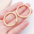 Two pieces of golden flat split rings for DIY keychains held in hand for scale - Gold Round Style (25820)