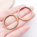 Hand holding two bronze metal split rings showing size for DIY keychain accessories - Antique Bronze Round Style (25823)