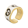 Detail of gold-plated open ring featuring white enamel and black heart patterns - White