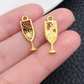 Macro shot of two golden champagne glass metal charms for DIY jewelry making and crafts - Bubbly Glass Shape