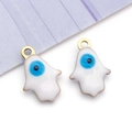 Detailed macro of white enamel Hamsa Hand charms with blue evil eye motifs for DIY jewelry - Hand Shape / White