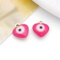 Close-up of pink enamel heart pendants with evil eye pattern and gold metal hooks - Heart / Rose Red