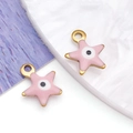 Detailed view of pink starfish evil eye charms with gold metal edges on textured stone - Pentagram / Pink