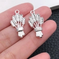 Silver wheat bundle alloy charms for DIY jewelry making shown on hand for scale - Barley Wheat Wine