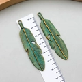 Detailed macro view of retro bronze feather pendants with green patina finish and leaf texture - Antique Patina Green (8272)
