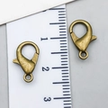 Pair of antique bronze alloy lobster clasps with jump rings shown on a size scale ruler - Antique Bronze