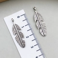Vintage silver feather pendants with fine details shown with a measurement ruler - Antique Silver (5036)