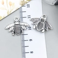 Antique silver bee charm for handmade jewelry measuring 2cm wide on a scale - Small Bee (7390)