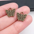 Vue rapprochée de pendentifs papillon en alliage bronze antique posés sur une main - Forme de Papillon 12x12mm (20161)