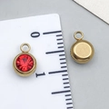 Macro view of a 6mm red zircon charm pendant on a scale for precise size reference - Gold - Bright Red