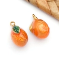 Détail macro de pendentifs kaki orange avec feuille verte et boucles dorées en métal - Pendentif Mangue 3D Jaune-Orange Transparente (T1603)