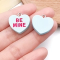 Handheld view of light blue resin heart pendants with Be Mine text and silver metal loops - 1.9x1.9cm (1.2g) / Lake Blue (Bemine)