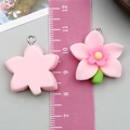 Macro detail of 3cm resin flower charms with pink petals, yellow stamens and metal rings - Orchid Style (24339)