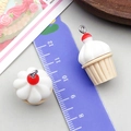 Macro shot of resin cupcake charms with metal loops and a ruler for size reference - Light Coffee Cream Cupcake (24088)
