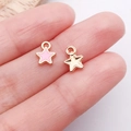 Pink enamel star charms and gold textured metal pendants held on fingertips - Pink Small Pentagram Style