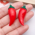 Handheld pair of miniature red chili resin pendants with green sepals and silver rings - Red Resin Chili (19699)