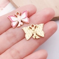 Pink ribbon butterfly alloy pendant for DIY jewelry, front and back view on hand - Pink Butterfly Ribbon Charm (24869)