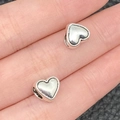 Silver alloy heart-shaped spacer beads shown on a finger for size reference in DIY jewelry - Heart Large Hole Bead (3956)