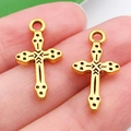 Macro shot of vintage gold cross charm with black engraved totems and ring bail - Patterned Cross Style (20365)