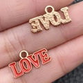 Golden and red enamel LOVE heart charm pendants held on fingers for size reference - 1 Piece LOVE Letter Style (21488)
