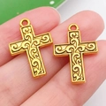 Golden vintage alloy cross pendant with floral engraving held on fingertips - Patterned Cross Style (20380)