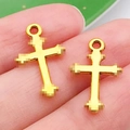 Set of two gold alloy cross charms for DIY jewelry making shown on fingertips - Cross Style (20383)