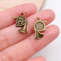 Detail view of small bronze French horn charms for DIY jewelry making on human hand - French Horn (20894)