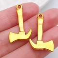 Golden alloy axe pendants for DIY jewelry making shown held in hand for size scale - Axe 26x15mm (20386)