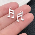 Silver musical note metal charms held on fingertip to show small scale for DIY jewelry - Double Music Note (20916)
