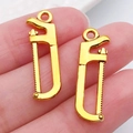 Golden handsaw alloy pendant for DIY necklaces and keychains in a shiny metal finish - Saw 25x8mm (20396)