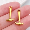 Golden hammer alloy charms for DIY jewelry making shown on finger for scale - Small Hammer 19x9mm (20401)