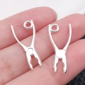 Mini breloques pinces en alliage argenté pour bijoux DIY posées sur un bout de doigt - Style Pince (20407)