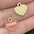 Pink heart-shaped pendant with XOXO text and golden metal charm on a fingertip - Pink Glitter Heart Letter (21527) / 13x13mm