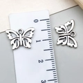 Macro view of two vintage silver-tone hollow butterfly pendants with measurement ruler - Hollow Butterfly Style (15826) / 14x10mm