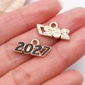 Macro d'un pendentif année 2027 en alliage doré avec émail noir présenté sur un doigt - Noir 2027