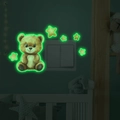 Luminous wall sticker showing a glowing cartoon bear and stars around a light switch in the dark - Green Glow (MG-YK035)